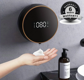 Black wall-mounted soap dispenser dispensing soap into a hand, with a 6-month warranty badge in the corner.